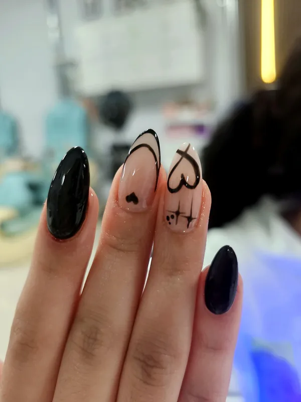 Almond nails in black with hand-painted hearts and sparkles